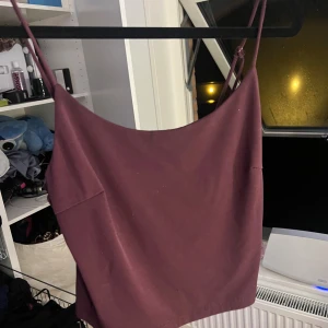 Vinröd linnetopp med smala axelband - Säljer en vinröd linnetopp med smala, justerbara axelband och rak halsringning. Toppen är croppad och har en enkel, stilren design som passar perfekt till jeans eller kjol. Materialet känns mjukt och lätt mot huden.