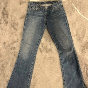 Levi's Demi Curve blå bootcut jeans - Blå Levi's Demi Curve jeans med bootcut och klassisk femficksdesign. Jeansen har snygga slitningar och kontrastsömmar, samt Levi's ikoniska bakfickor med broderad båge. Tillverkade i jeansmaterial med en skön passform. Pris kan diskuteras vid snabb affär! Midjemått: 37/38cm Grenhöjd: 19cm  Innerbensmått: 72,5cm Totallängd: 96/97cm
