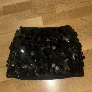 Svart glittrig paljettkjol - Supersnygg svart kortkjol med stora glittrande paljetter som verkligen fångar ljuset. Kjolen har en tight och snygg passform. Materialet är mjukt och stretchigt🩷 Säljer eftersom den inte kommer till så mycket användning 