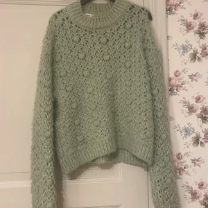 Ljusgrön stickad tröja - Säljer en mysig ljusgrön stickad tröja med ett vackert mönster. Tröjan har långa ärmar och ribbstickade muddar vid ärmslut och nederkant. Perfekt för kyliga dagar! Jättefin verkligen 
