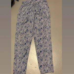 Blå paisleymönstrade byxor från Glitzia - Byxorna har en relaxed passform och är gjorda i mjukt bomullsmaterial. Perfekta för dig som gillar att sticka ut med coola mönster och bekväma plagg.