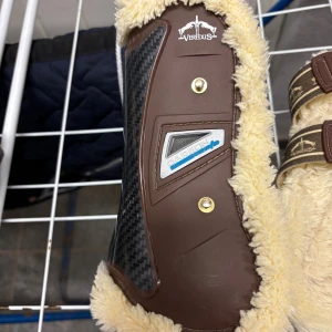 Bruna Veredus ridhandskar med fuskpäls - Säljer ett par bruna Veredus fram och bakskydd med fuskpäls i storlek S. sparsamt använda och ändrats använda på tävling, har passat C och stor D ponny, hade dock passat en storhäst med smala ben. Säljes då dem inte passar nya hästen! Säljer dem helst tillsammans! Nypris 3940kr så tänker mig 2400kr.