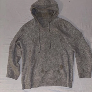 Grå kashmire hoodie  - Säljer denna grå kashmire tröja då jag har använt den ett tag fläckarna du ser på bilden är nog parfym fläckar går enkelt bort i en tvätt. Vet tyvärr inte vilket märke men nypris är 899kr