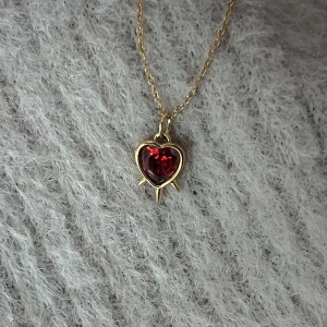 Three Swords - Crimson Heart - 0,9 cm rött hjärta piercat av tre svärd. Justerbar 50 cm kedja, minimalistiskt och iögonfallande.
