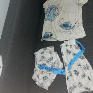 Stitch pyjamas sett - 3- delad Pyjamas sett med färgglada Stitch-motiv från Disney.T-shirt, shorts & byxor. Materialet känns mjukt och skönt, perfekt för chill dagar. Trycket är i blått, rosa och svart och ger en lekfull vibe. Går ej att köpa separat, kommer i ett sett. 
