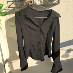 Svart skjorta med snörning i ryggen - svart skjorta med långa ärmar, krage och snygg snörning i ryggen som går att dra åt så att de. passar XS oxå (den är S). Aldrig använt, men tycker den är jätte fin ändå