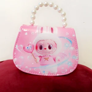 Söt rosa handväska med pärlhandtag - Supergullig rosa handväska med ett tryck av en tecknad figur i kanindräkt och hjärtan. Väskan har ett pärlhandtag och en avtagbar axelrem i rosa. Perfekt för dig som gillar kawaii-stil och vill ha något unikt och lekfullt.