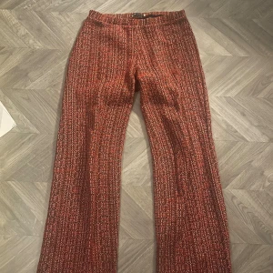 Röda rutiga byxor från Zara M - Säljer ett par röda rutiga byxor från Zara i storlek M. Byxorna har ett rakt snitt och är tillverkade i ett grovt, stickat material med inslag av vitt och svart. De har en midwaist passform och ett coolt mönster som sticker ut.