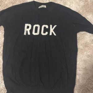 Svart stickad tröja Zadig & Voltaire - Cool svart stickad tröja från Zadig & Voltaire med vit text 'ROCK' framtill. Tröjan har rund hals, ribbade muddar och långa ärmar.