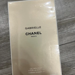 Gabrielle Foaming Shower Gel Chanel - Lyxig skummande duschgel från Chanel Gabrielle i en elegant champagnefärgad förpackning. Perfekt för dig som vill ha en exklusiv känsla i badrummet och älskar doften av Chanel. Innehåller 200 ml och har en stilren design med svart text.