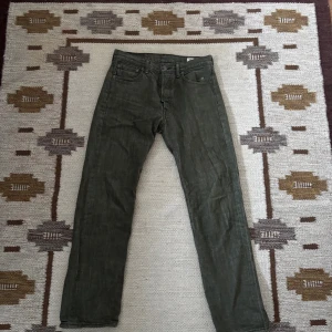 Levi's 501 gröna jeans W30 L32 - Säljer ett par klassiska Levi's 501 jeans i en snygg mörkgrön färg. Modellen har rak passform, fem fickor och knappgylf. Jeansen är tillverkade i slitstarkt bomullsmaterial och har den ikoniska läderpatchen bak i midjan.