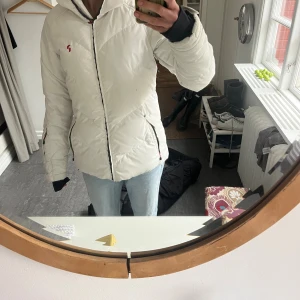 Vit Peak Performance dunjacka S - Säljer en snygg vit dunjacka från Peak Performance i storlek S. Köpt i Åre! Jackan har quiltad design, dragkedja framtill och två fickor med dragkedja. Perfekt för kalla dagar och har en stilren look med diskret logga på bröstet. Se lite defekt på framsidan på bilderna. 💖SÅ varm och mysig jacka pefekt att åka skidor och ha på vintern.