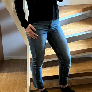 Blå croppade jeans från Gina Tricot - Snygga blå jeans med croppad längd och råa, fransiga benslut från Gina tricot. Jeansen är i ett straight snitt och hög midjade.