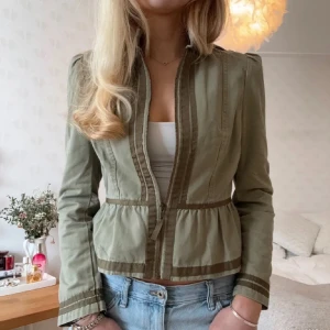 Grön vårjacka  - Snygg grön croppad jacka med dragkedja framtill och markerad midja. Jackan har långärmade ärmar, ståkrage och coola sömdetaljer längs kanterna. Perfekt till jeans och ger en chill vibe till din outfit.