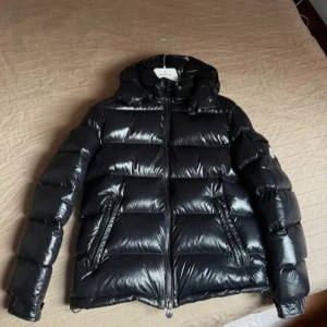 Svart Moncler pufferjacka med huva - Säljer en svart pufferjacka från Moncler. Äkthetsbevis och kvitto finns. Skickar fler bilder om det behövs. 