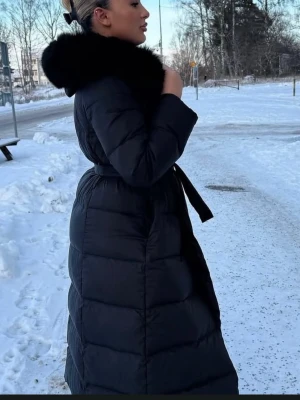 Svart lång dunjacka med päls - (Pris kan diskuteras) Säljer en svart lång dunjacka med päls. Jackan   är perfekt för kalla vinterdagar. 