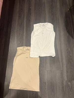 Två ärmlösa linnetoppar från Oysho XL - Säljer två stilrena ärmlösa linnetoppar från Oysho i storlek XL. Ena toppen är vit och den andra är beige, båda med rund hals och diskret Oysho-logga framtill. Perfekt för chill dagar eller när du vill ha en enkel look. Materialet är mjuk bomull som känns skönt mot huden.