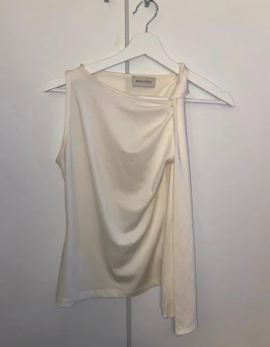Vit topp från Anna Field, xs - Säljer en vit topp från Anna Field med cool knyt-detalj på axeln. Materialet känns mjukt och stretchigt