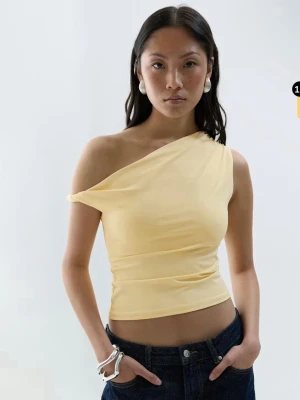 Gul oneshoulder topp från Gina Tricot - Snygg ljusgul oneshoulder topp från Gina Tricot. Modellen är croppad med en asymmetrisk axel och sitter tight mot kroppen. Materialet är mjuk och stretchig bomull som känns skön mot huden. Perfekt att styla med jeans eller kjol för en trendig look.