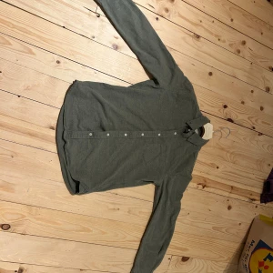 Grå skjorta från A Day's March M - Snygg grå skjorta från A Day's March i bomull. Klassisk modell med knappar hela vägen, bröstficka och button down-krage. Perfekt passform i custom fit och långärmad design. Enkel och stilren look som funkar till det mesta.