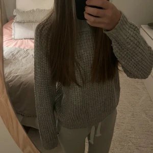 Grå stickad tröja från Lager 157 - Mysig grå stickad tröja från Lager 157 med grov struktur och ribbad hals. Tröjan har långärmade ärmar och en relaxed passform som är perfekt för chill dagar. Materialet är mjukt och värmande, och färgen är ljusgrå vilket gör den enkel att matcha med allt. Tröjan är i storlek L men sitter precis som S!