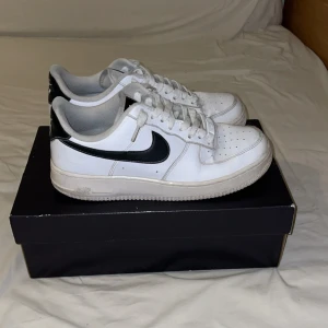 Nike Air Force 1 vit/svart - Nike Air Force 1 LV8 sneakers i klassisk vit med svarta detaljer och swoosh. Låg modell med rund tå, snörning och platt sula. Tillverkade i skinn med grå insida och svart häl. Perfekt för dig som gillar stilrena och tidlösa sneakers.