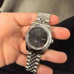 Seiko Mod DateJust Arabic Dial 39mm - Seiko Mod DateJust med arabisk urtavla i grått och en klassisk 39 mm boett. Klockan är byggd i rostfritt stål, har safirglas och drivs av det automatiska NH35-verket – känt för sin precision och tillförlitlighet. En stilren och unik klocka med lyxig känsla