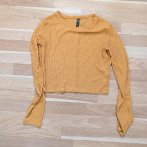 Gul stickad magtröja från Zara - Säljer en snygg gul stickad magtröja från Zara i storlek S. Tröjan har ett coolt mönster, är croppad och har långa ärmar. Perfekt för dig som gillar trendiga och bekväma plagg med lite extra edge. 