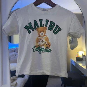 Vit t-shirt med nalle och Malibu-tryck - Säljer en barn tröja väldigt fint skick 