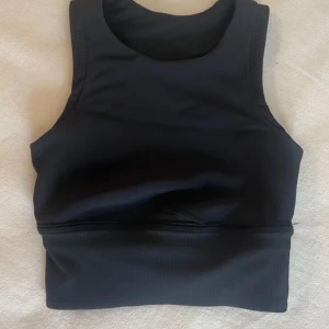 Svart croppad linnetopp Lululemon  - Superfin  och bekväma träningstopp från Lululemon i svart. Den har ett ribbat material och tight passform, passar för både träning och vardag. Nypriset var runt 600-700kr