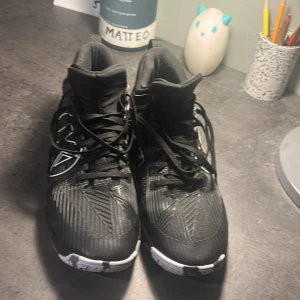 Svarta Matrixx sneakers med högt skaft - Säljer ett par svarta sneakers från kempa med högt skaft och coola vita detaljer på sidorna och sulan. Skorna har snörning och en mönstrad ovandel med grafiska linjer. Perfekt för dig som gillar sportig och modern stil.