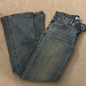 Blå jeans med slitningar,  lowwaist bootcut - Snygga blå jeans från Perfect Jeans i bootcut fit med klassisk femficksdesign. Jeansen har coola slitningar och hål på benen för en avslappnad vibe. Materialet är robust denim och färgen är en tvättad blå ton. Passar dig som gillar en enkel och tidlös look.