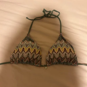 Mönstrad trekantsbikini med snörning  - Snygg trekantsbikini med färgglatt mönster i grönt, gult, brunt och rosa. Bikinin har knyt i nacken och ryggen samt en liten metallberlock framtill. Det är storlek L men är liten i storlek, skulle säga att det är en S/M