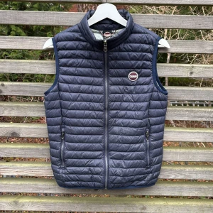 Mörkblå dunväst från Colmar - Snygg mörkblå dunväst från Colmar med quiltad design och ståkrage. Västen har två dragkedjeförsedda fickor och ett Colmar-märke på bröstet. Insidan är ljusgrå och materialet är lätt och smidigt, perfekt för lager-på-lager. Passar dig som gillar sportig och clean stil.
