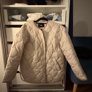 Beige quiltad jacka från Bik Bok - En snygg vår/ höst jacka som passar till ALLT! Aldrig använd - inga defekter.                                        Den är beige, har två fickor och knappar framtill. Jättesnyggt mönster. 