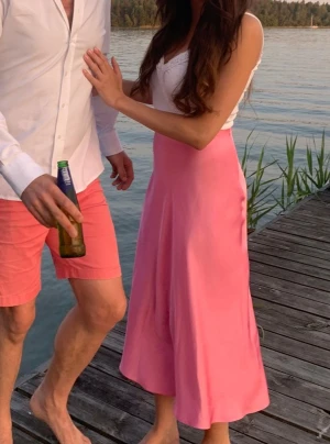 Rosa långkjol i satin  - Fin rosa kjol i tunnt satinmaterial. Passar dig som gillar stilrena och färgglada plagg.