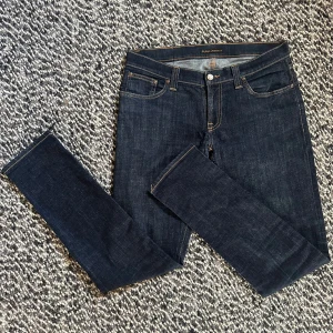 Nudie jeans 31/32 - Ett par supersnygga Nudie Jeans med en snygg wash och bra passform!😄Nudie jeansen är i modellen Tight Long John. Blir perfekta för höst och vinter med den mörkare washen. Litet slitage på ena bakfickan(syns på bild) men inget man tänker på i verkligheten. Annars är dem nästintill nya!🤩 Nypris: ca 1400kr. Mitt pris 549kr, men kom gärna med prisförslag då priset inte är hugget i sten!