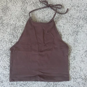 Brun halterneck linnetopp från Bik Bok - Säljer en brun halterneck linnetopp från Bik Bok i storlek S. Toppen har knyt i nacken och är ärmlös med en croppad passform. Endast använd fåtal gånger och i väldigt fint skick. 