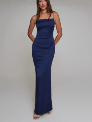 Marinblå balklänning - Säljer en marinblå långklänning med smala axelband och rak halsringning. Klänningen har en figurnära passform och öppen rygg, vilket ger en elegant och stilren look. Har tidigare använt den som balklänning!! 