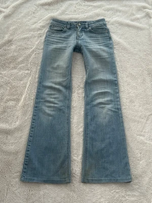 Lågmidjade utsvängda jeans  - Ett par lågmidjade jeans från Lotus clone i storlek W25 L33, vilket motsvarar en vanlig XXS. Rakt över midjemått: ca 34cm. Innebenslängd: ca 75cm. Något smutsiga vid ben, går bort i tvätt. Litet hål/slitet tyg bak men går att sy ihop eller användas ändå (syns inte när man använder dom). Blivit för små för mig. Jag fraktar inom 24h. Obs, PostNord prioriteras. Se liknande plagg i min profil!