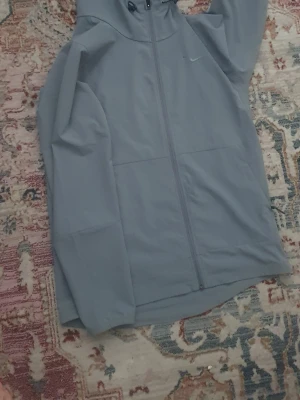 Grå Nike Vindjacka - Köpte den begagnad och säljer den för 450 pris kan diskuteras, Har en liten fläck från fyrverkerier bredvid loggen men syns inte från långt bort.