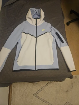 Nike Tech Fleece Hoodie – Blå/Vit, Nästan Ny! - Säljer min Nike Tech Fleece-hoodie i snygg blå och vit färg. Den har knappt varit använd och är i perfekt skick. Inga fläckar eller skador. Riktigt mjuk och bekväm.
