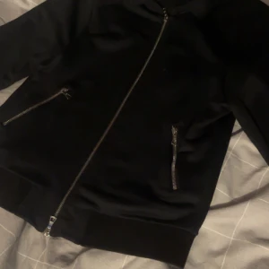 Svart zip från Limitato - Svart zip från Limitato med fett tryck av Jimi Hendrix på ryggen. Jackan har silvriga dragkedjor framtill och på fickorna, ribbade muddar och en clean look. Väldigt mjuk och skön att bära. Jag har endast använt den 10 gånger max. Storlek S och skulle säga passar mellan 170-178cm. Skriv vid frågor!