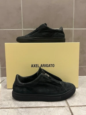 Axel Arigatos  - Axel Arigato Clean 90 Zip. Sällsynta Arigatos i väl använt skick. Inga andra skador finns förutom vid hälen. Box medföljer inte ❌Skriv i DM för fler bilder 📝