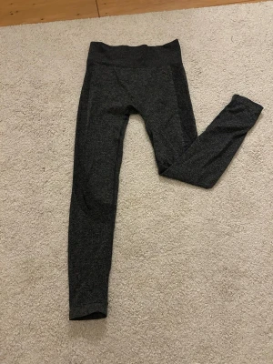 Mörkgrå leggings från stadium  - Säljer ett par mörkgrå leggings från stadium i stretchigt material. De har medel hög midja och är perfekta för träning eller chill. Tillverkade i polyester och elastan för skön passform och rörelsefrihet.