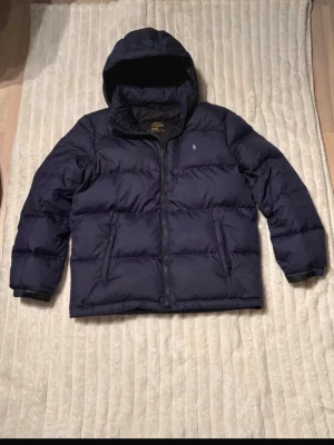 Mörkblå pufferjacka från Polo Ralph Lauren - Säljer en mörkblå pufferjacka från Polo Ralph Lauren i storlek S. Den är knappt använd, passar mig som är 171cm och bär storlek S. Diskuterbart pris vid snabb affär!💕
