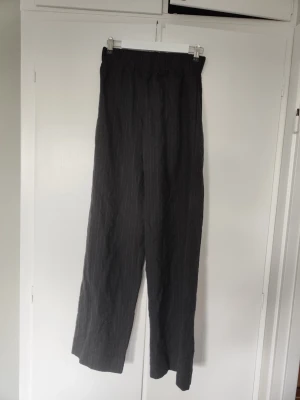 Svarta randiga byxor från Gucci - Säljer ett par svarta Gucci byxor i ull med tunna vita ränder och elastisk midja. Byxorna har en avslappnad passform. Diskret Gucci-logga broderad vid midjan. Har använts sparsamt. 