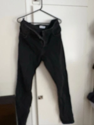 Svarta jeans från Woodbird - Säljer ett par svarta jeans från Woodbird med klassisk femficksdesign och smal passform. Jeansen har dragkedja och knapp framtill, raka ben och är tillverkade i slitstarkt bomullsmaterial. Perfekta för dig som gillar stilrena och enkla jeans.