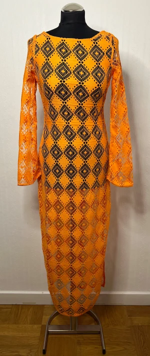 Orange strandklänning från H&M Divided - Supersnygg orange strandklänning från H&M Divided i storlek XS. Klänningen har ett coolt rutigt mönster, långärmade ärmar och öppen rygg med knytband. Materialet är syntet och klänningen har en figurnära passform som verkligen sticker ut. Aldrig blivit använd tyvärr då den suttit tajt över bysten… 