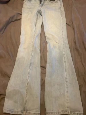 Ljusblå bootcut jeans - Säljer ett par ljusblå jeans med bootcut passform. Jeansen har klassisk femficksdesign och är tillverkade i ett mjukt denimtyg. Perfekta för dig som gillar retrovibbar och vill ha ett par riktigt snygga jeans med utsvängda ben. Har använt 2-4gånger, storlek XXS